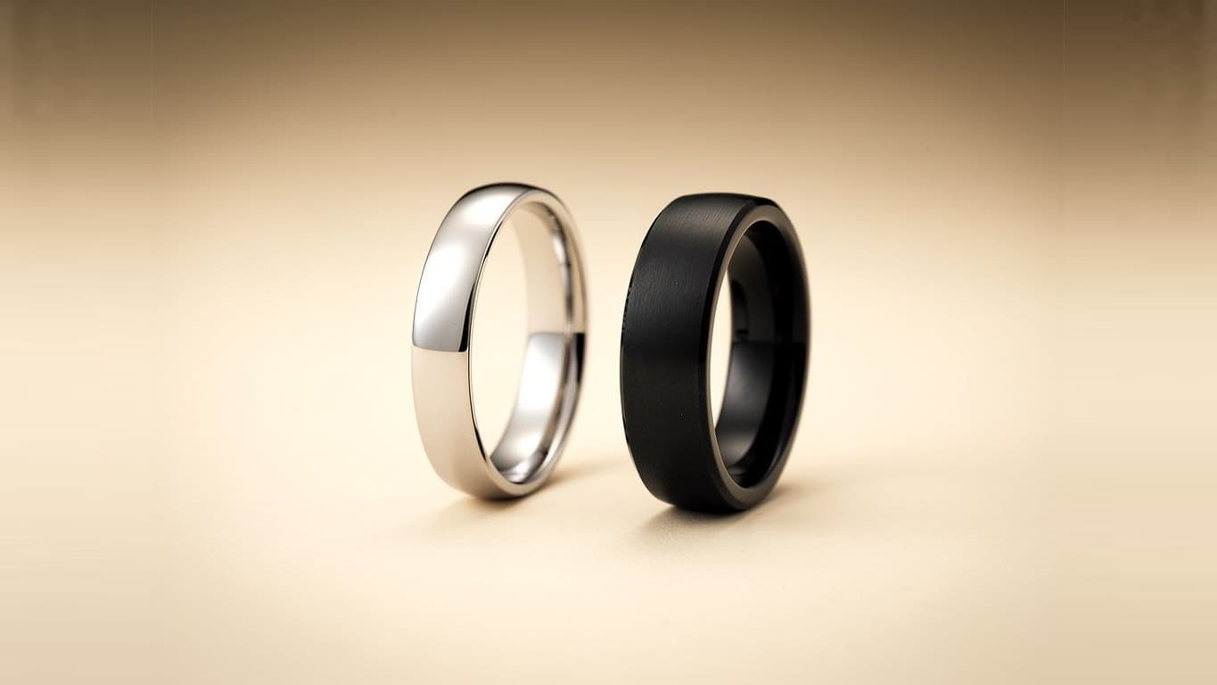 A slim silver finger ring beside a thick matte black Rodin band.
